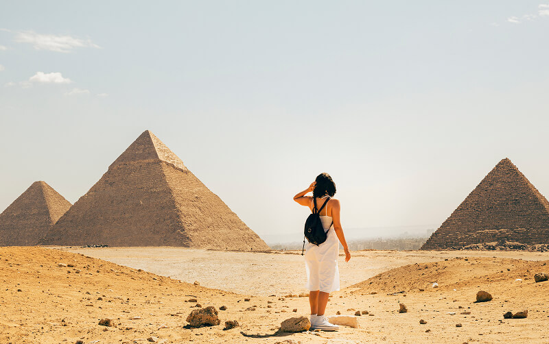 woman with backpack standing in front of pyramids in Egypt