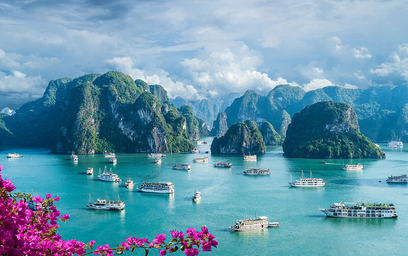 boats in front of limestone cliffs of Ha Long Bay in Vietnam